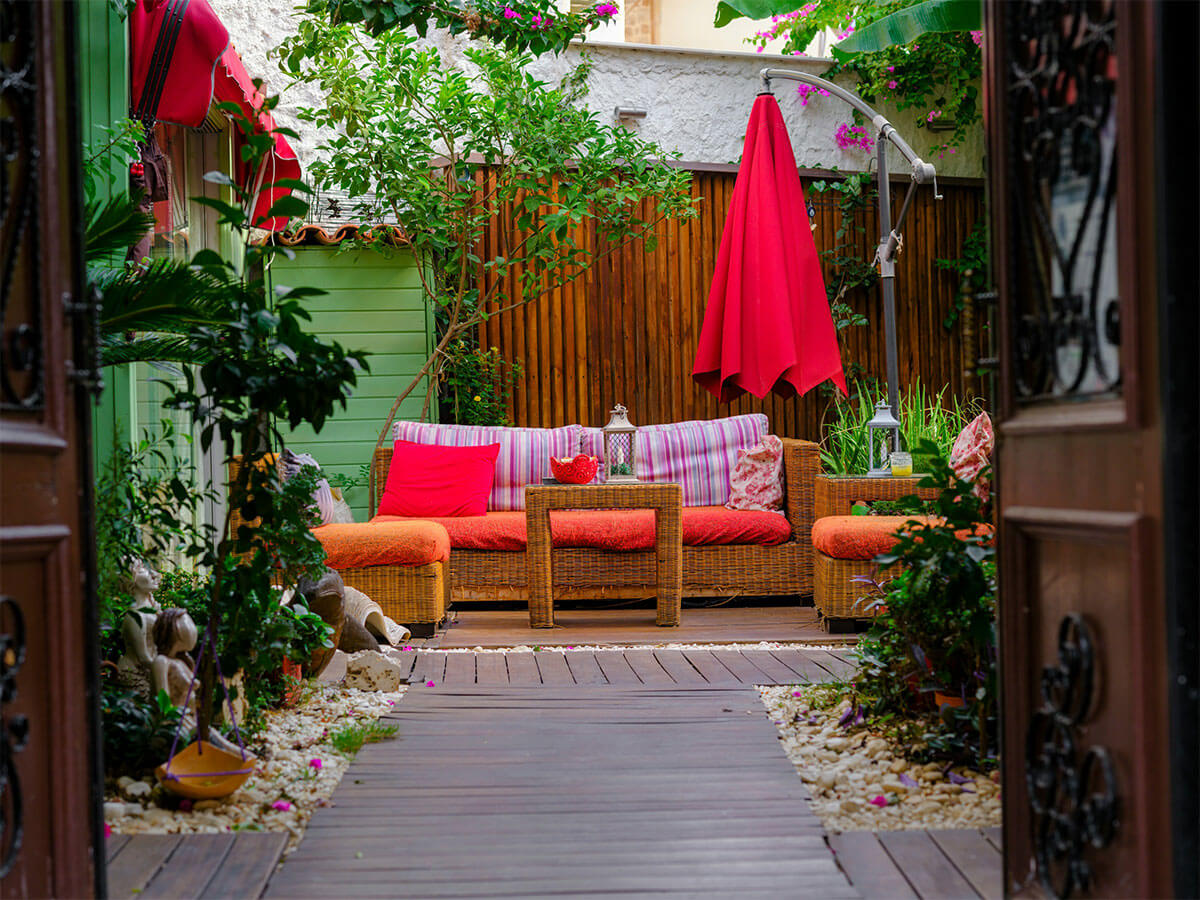 Colorful small garden with pink and orange accent colors on the sofa cushions and parasol.